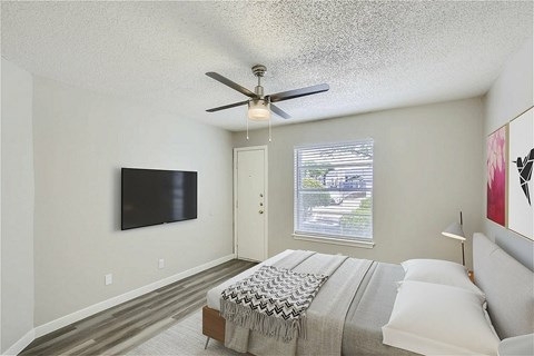 A bedroom with a large bed and a flat screen TV mounted on the wall.