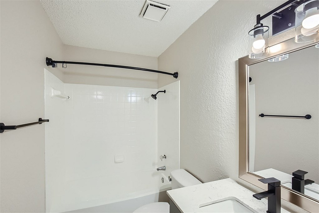A white bathroom with a sink, mirror, and shower.