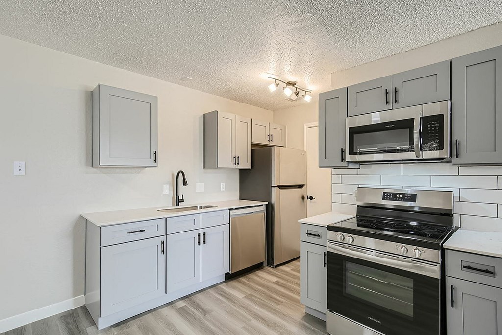 A kitchen with white cabinets and black appliances.