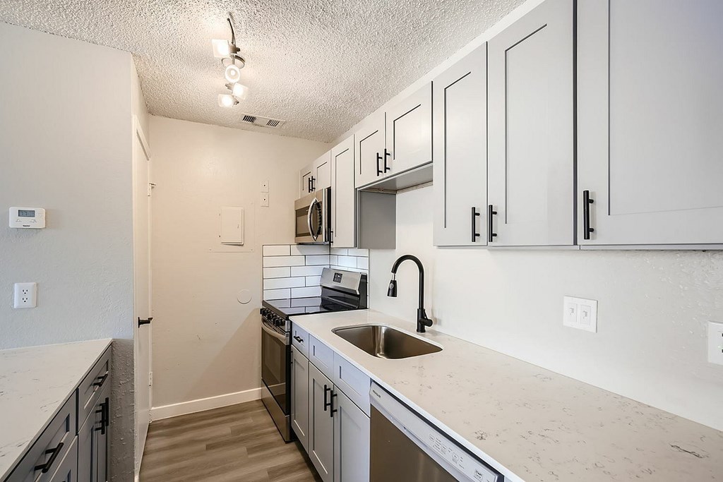 A kitchen with white cabinets and a marble countertop.