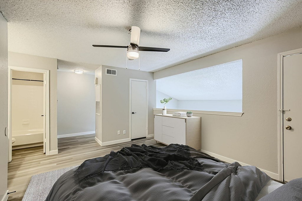A bedroom with a bed in the foreground and a window showing a view of the outside.