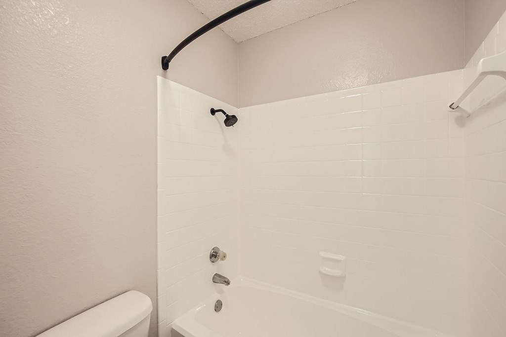 A white bathroom with a tub and toilet.