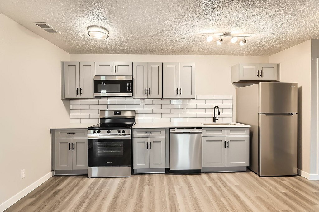 A kitchen with a stove, oven, microwave, dishwasher, and refrigerator.