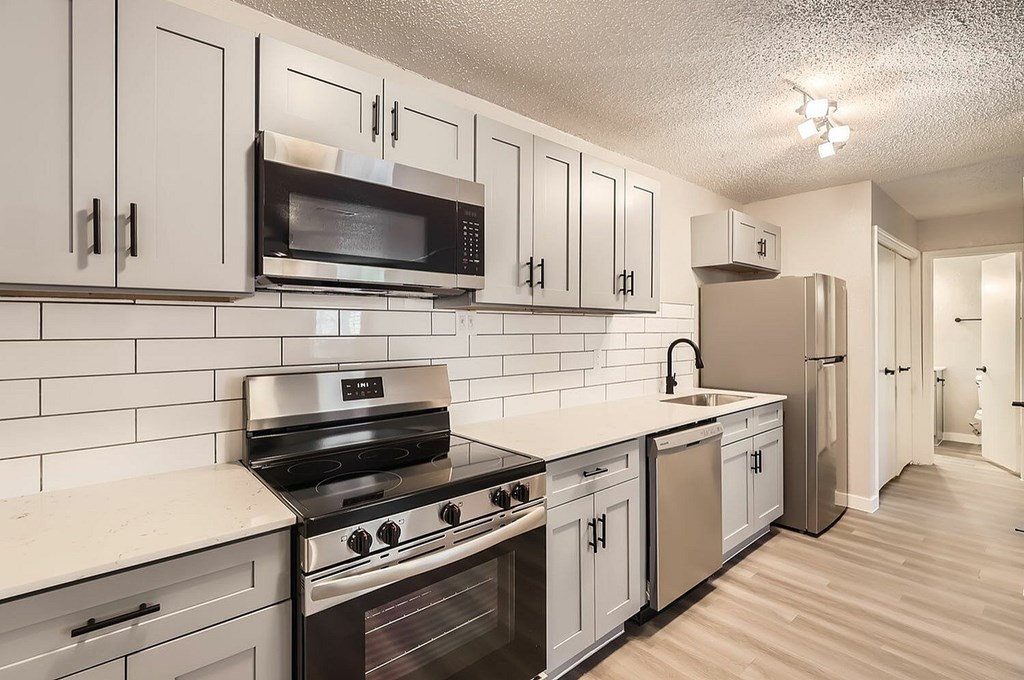 A kitchen with white cabinets and black appliances.