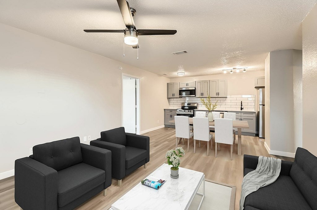 A living room with a black sofa, two armchairs and a dining table set up.