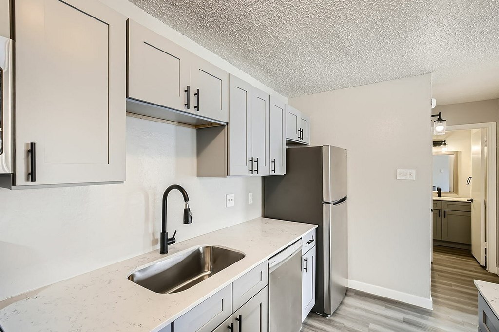 A kitchen with a sink and a refrigerator.