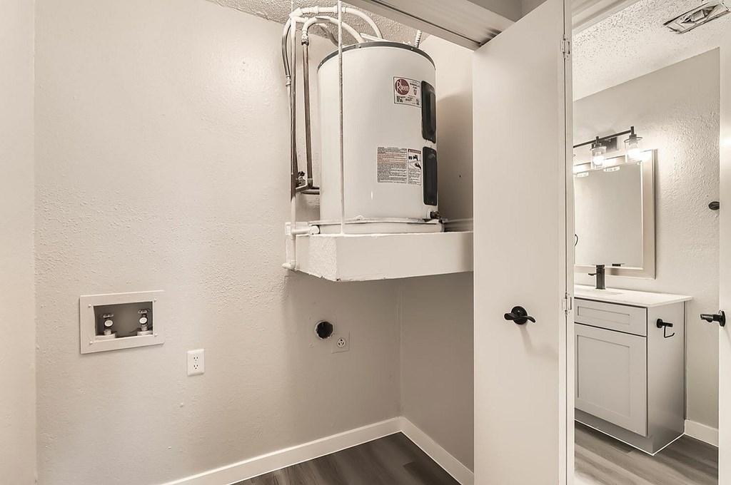 A white bathroom with a water heater mounted on the wall.
