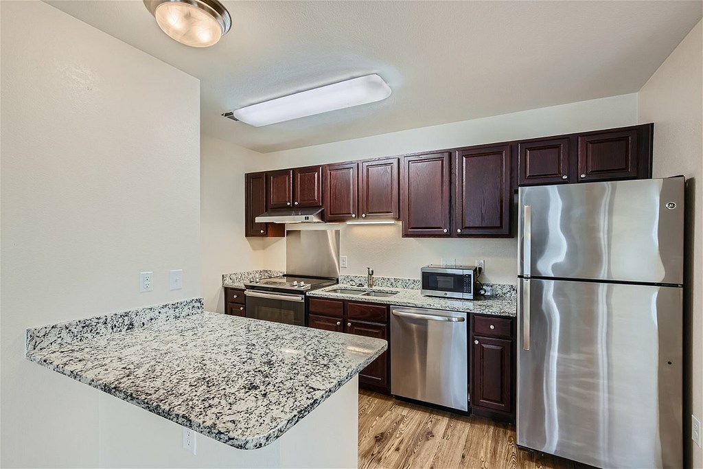 A kitchen with a granite countertop and stainless steel appliances.
