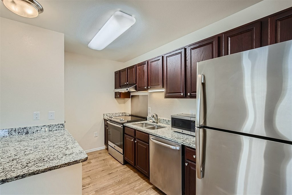 A kitchen with a granite counter top and stainless steel appliances.