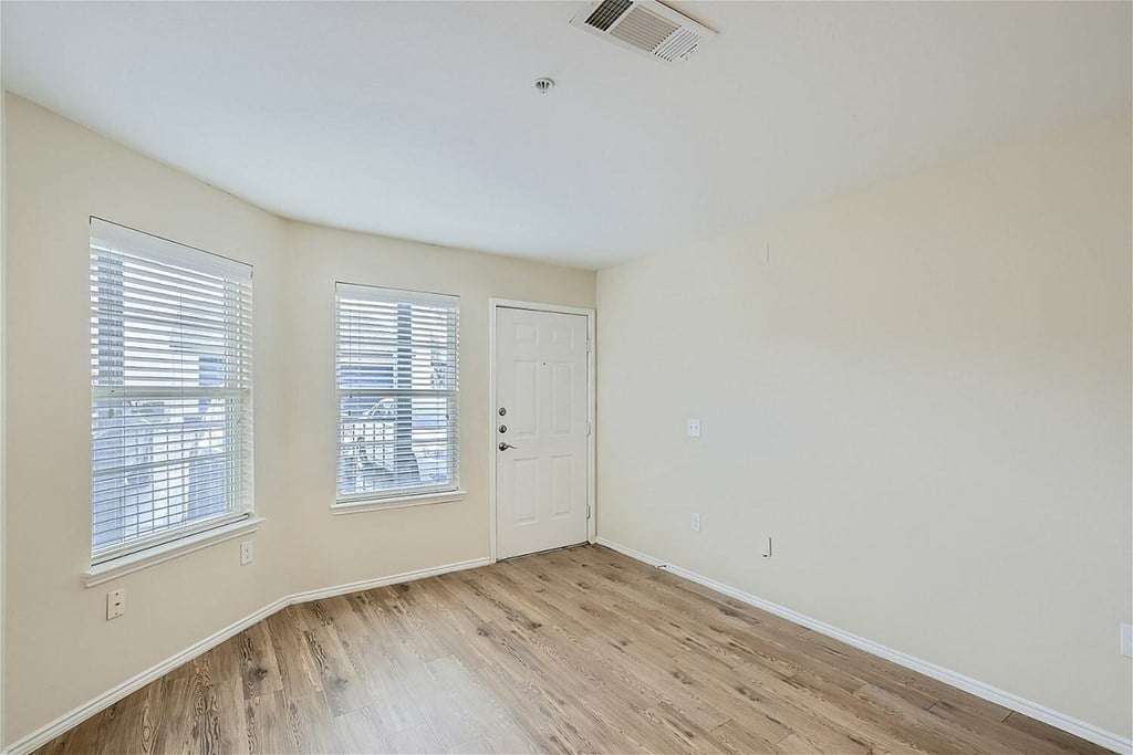 A room with a white door and two windows with blinds.