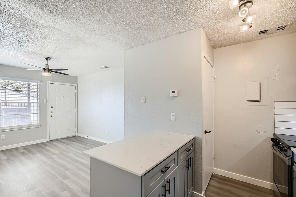 A kitchen with a white countertop and grey cabinets.