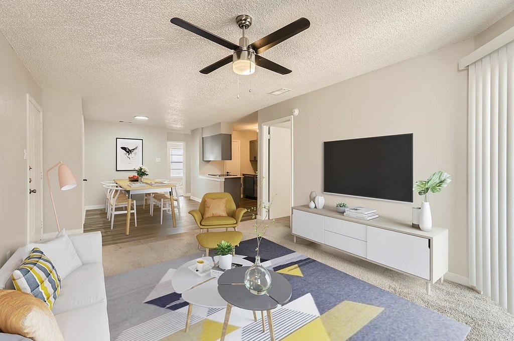 A living room with a ceiling fan and a flat screen TV.