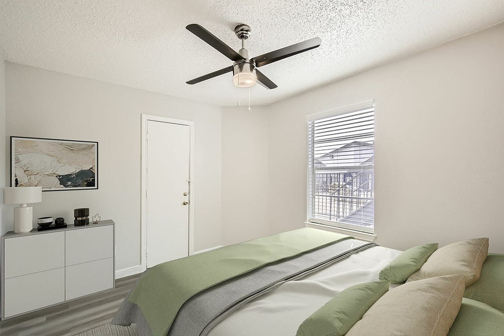 A bedroom with a bed, a ceiling fan, and a window with blinds.