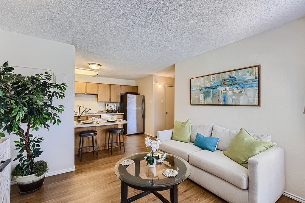 A living room with a white couch and a painting on the wall.