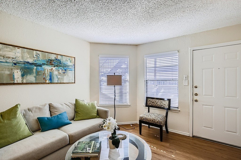 A living room with a couch, a chair, and a painting on the wall.