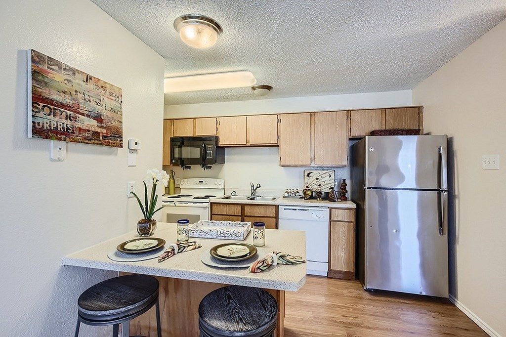 A kitchen with a refrigerator, microwave, and oven.