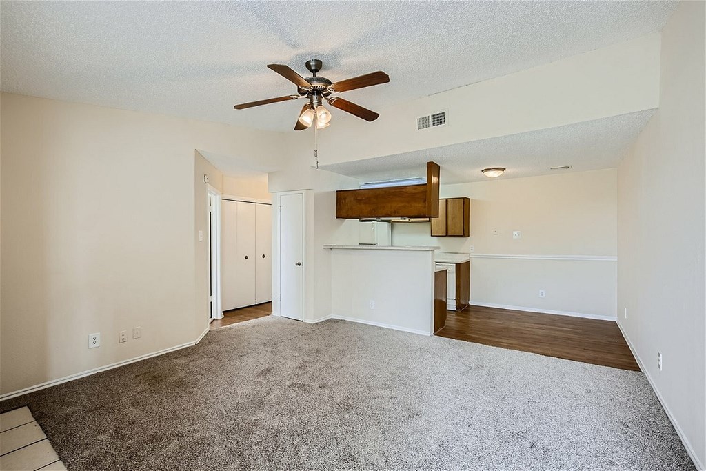 A spacious room with a ceiling fan and a bar area.