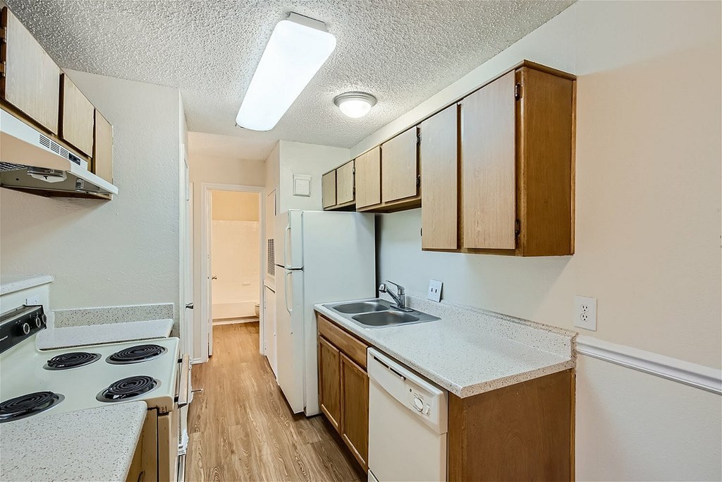 A kitchen with white appliances and wooden cabinets.