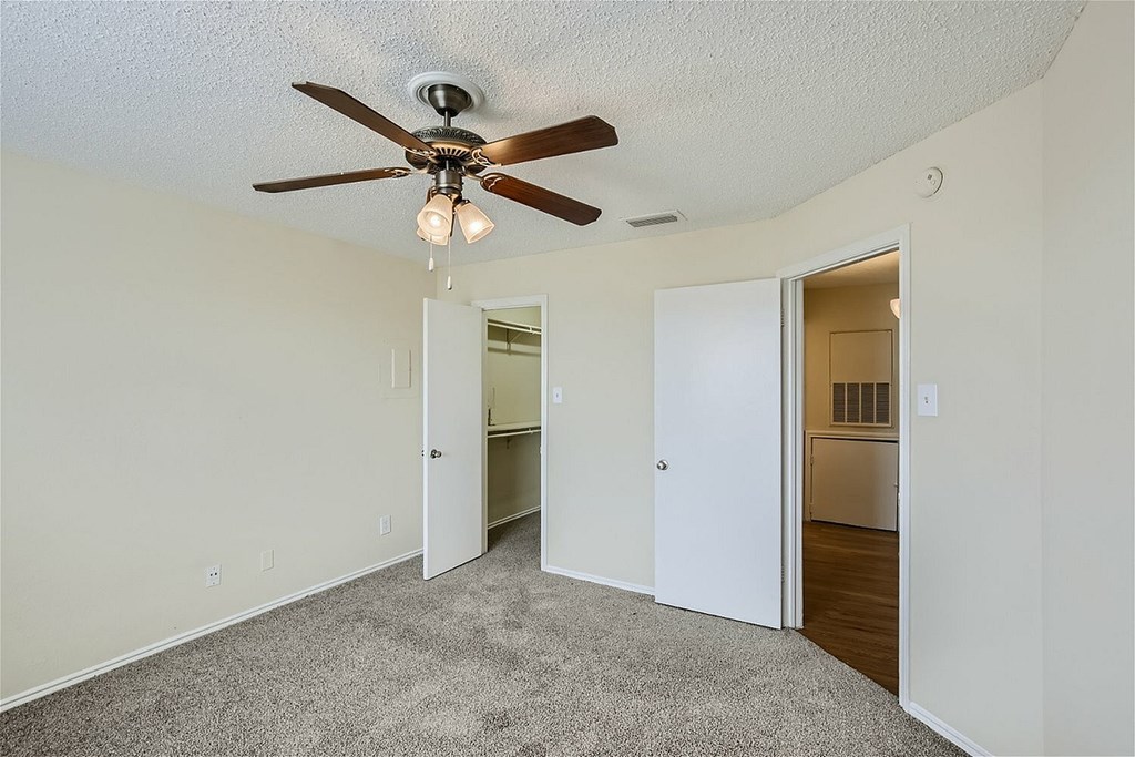 A room with a ceiling fan and carpeted floor.
