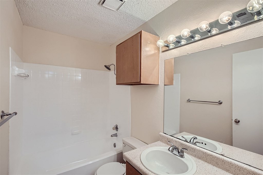 A bathroom with a white sink and a white toilet.