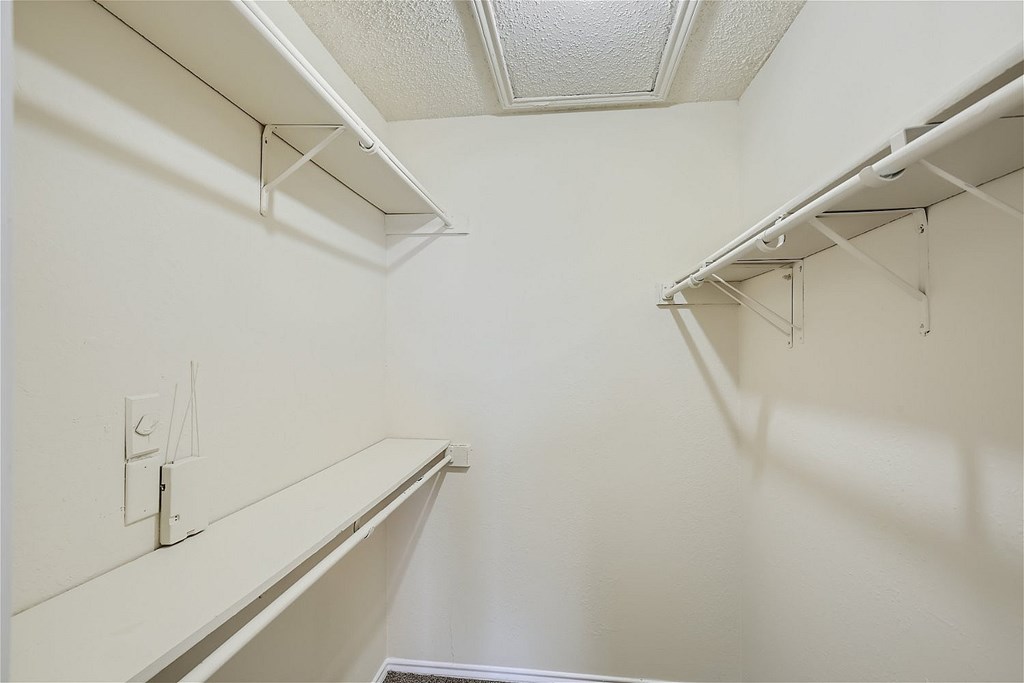 A white closet with a light switch and a light on the wall.