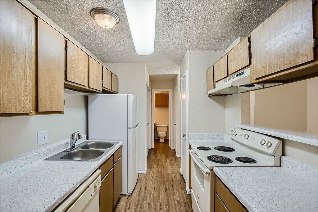 A kitchen with a white stove top oven and a white refrigerator.
