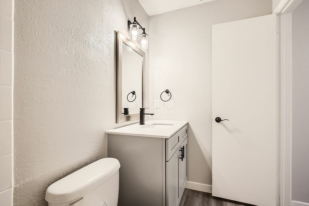 A white bathroom with a toilet, sink, and mirror.