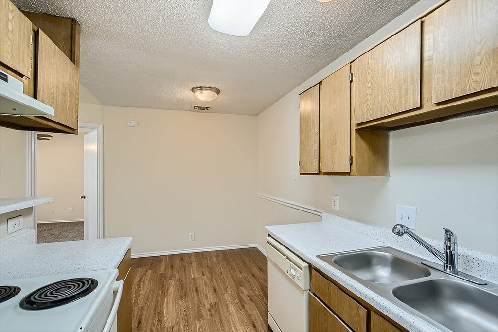 A kitchen with a white stove top oven and a white dishwasher.