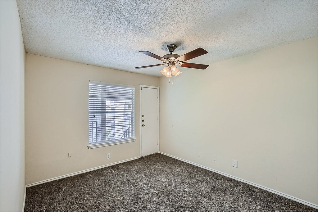 A room with a ceiling fan and carpeted floor.