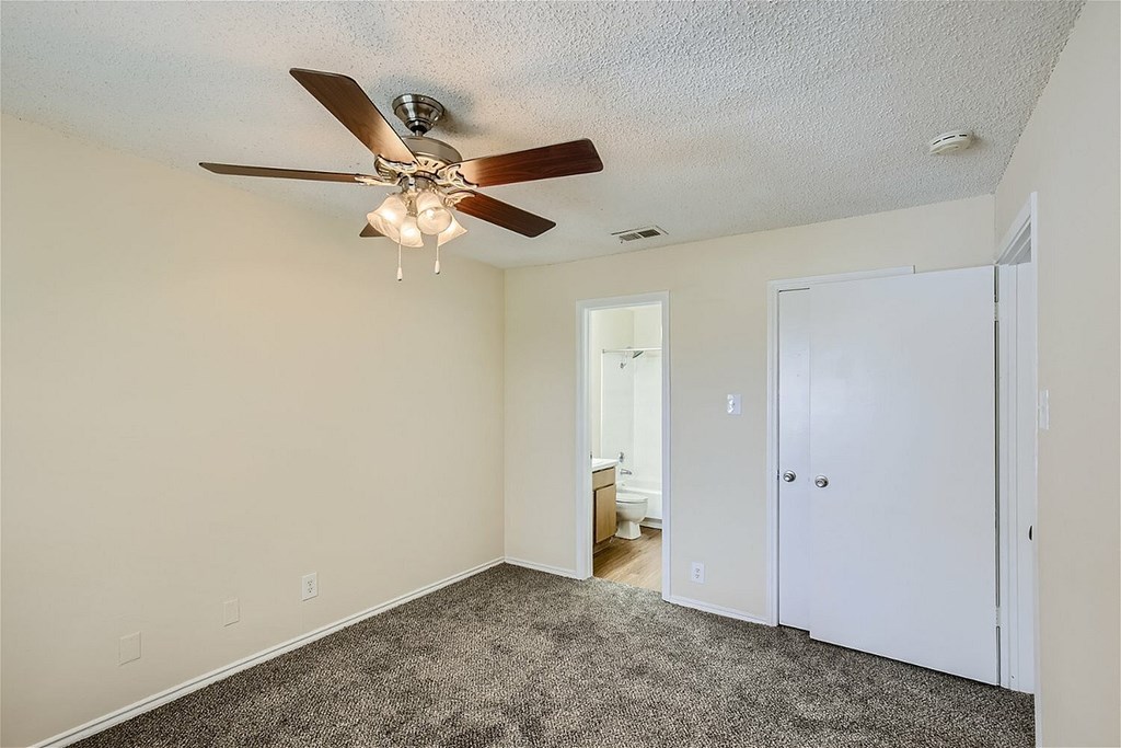 A room with a ceiling fan and carpeted floor.
