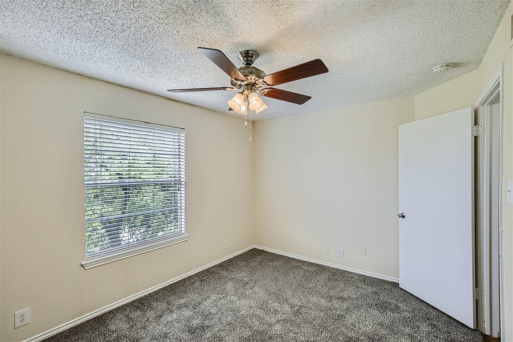 A room with a ceiling fan and a window with blinds.