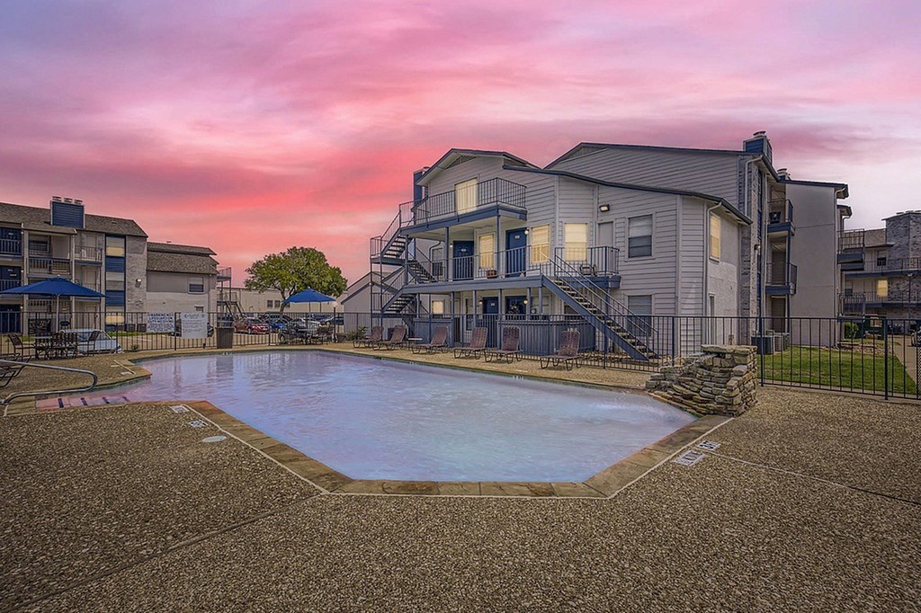 A swimming pool surrounded by apartment buildings at dusk.