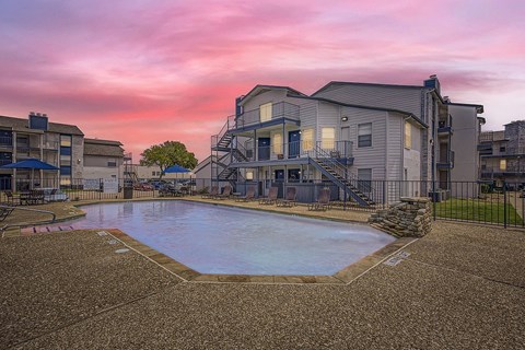 A swimming pool surrounded by apartment buildings at dusk.