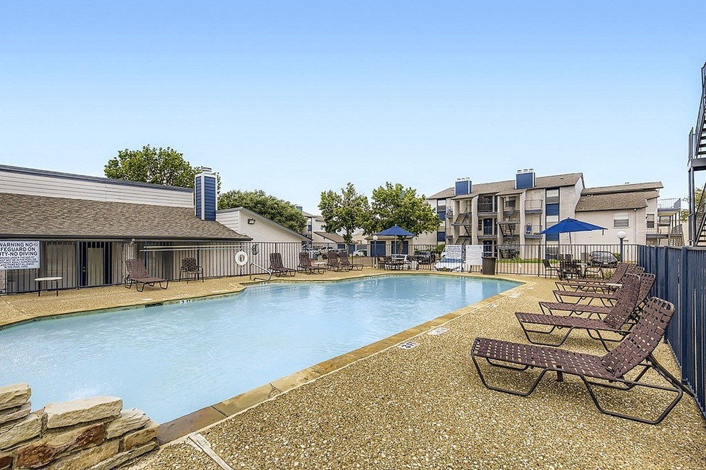 A large outdoor swimming pool surrounded by lounge chairs and umbrellas.