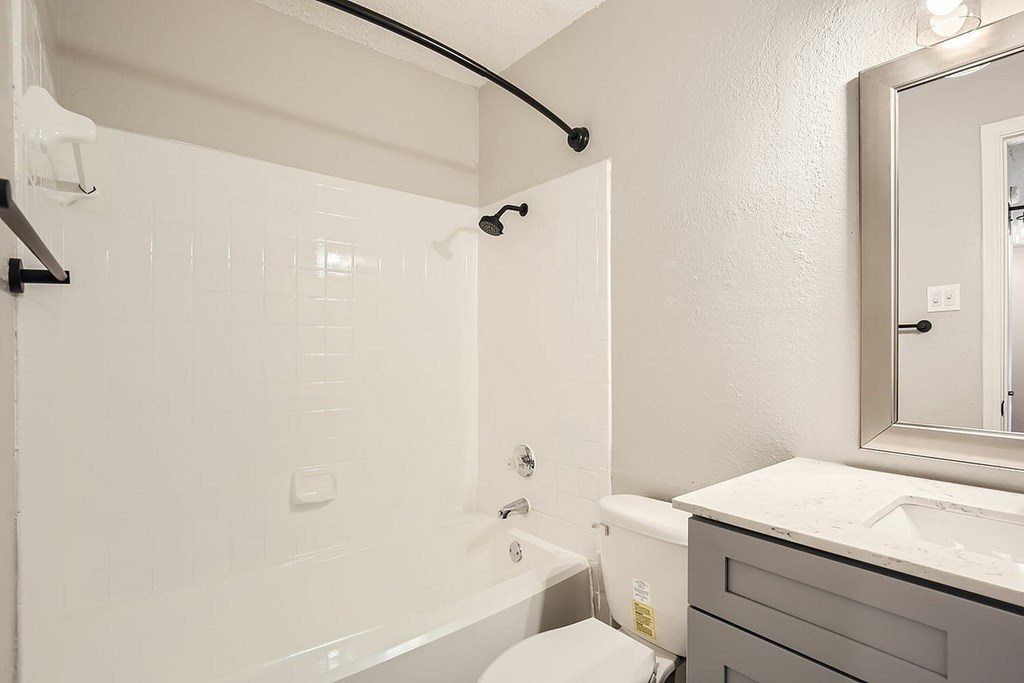 A white bathroom with a toilet, sink, and shower.