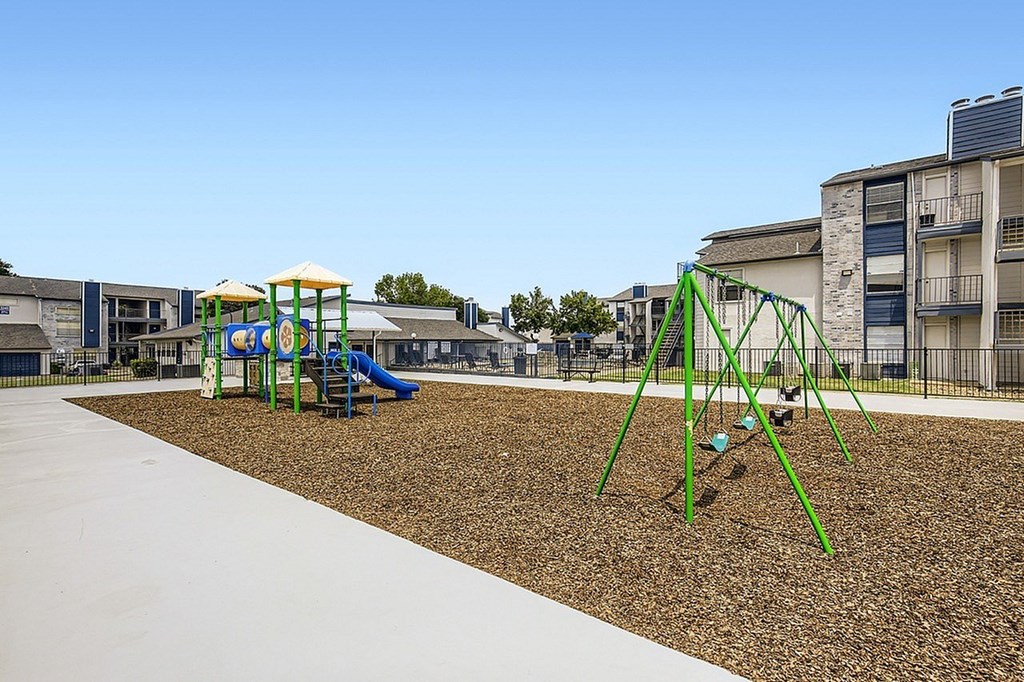 A playground with a green swing set and a blue slide.