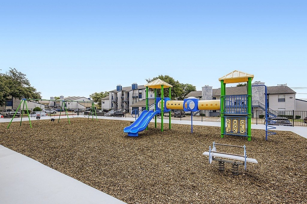 A playground with a blue slide and a green and yellow structure.