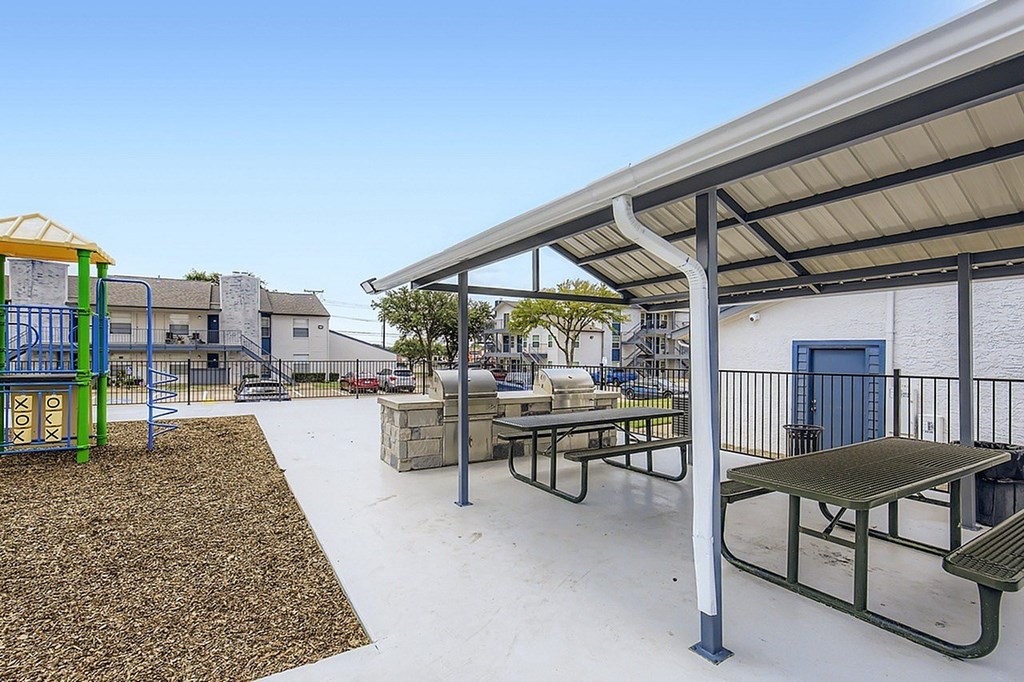 A playground with a slide and picnic tables.
