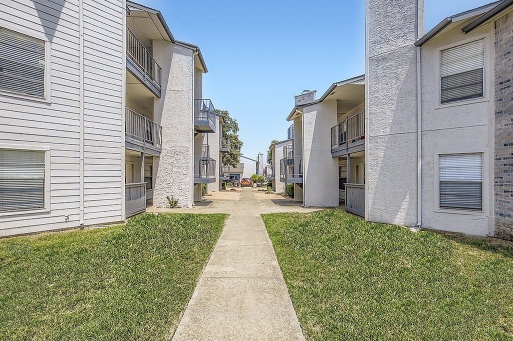 A concrete pathway leads between two rows of apartment buildings.
