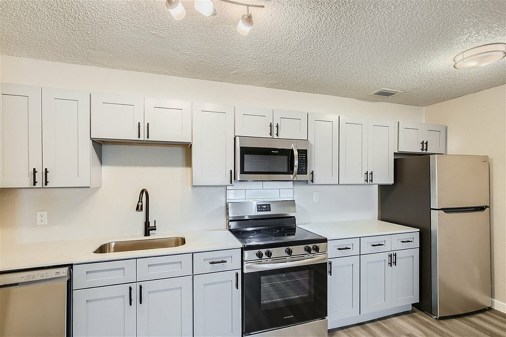 A kitchen with white cabinets and black appliances.