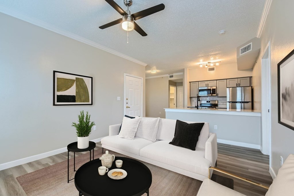 A living room with a white couch, a black coffee table, and a ceiling fan.
