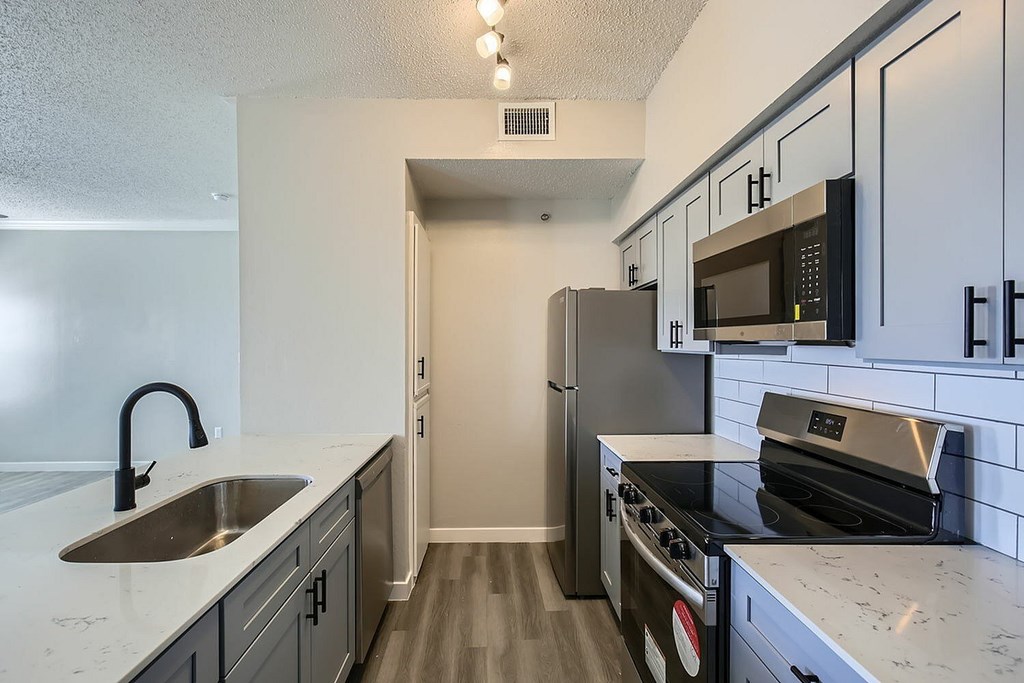 A kitchen with a sink, stove, and refrigerator.