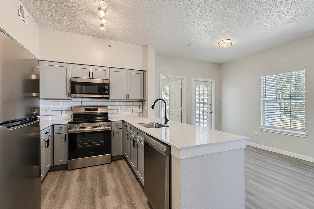 A kitchen with a white counter top and stainless steel appliances.