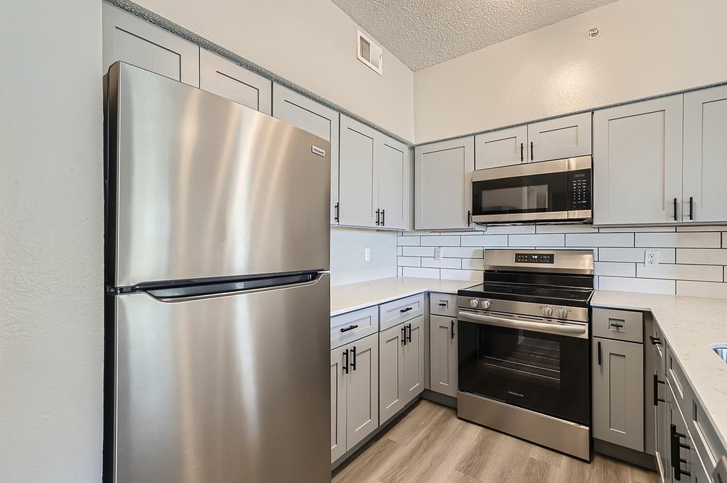 A modern kitchen with a stainless steel refrigerator and oven.