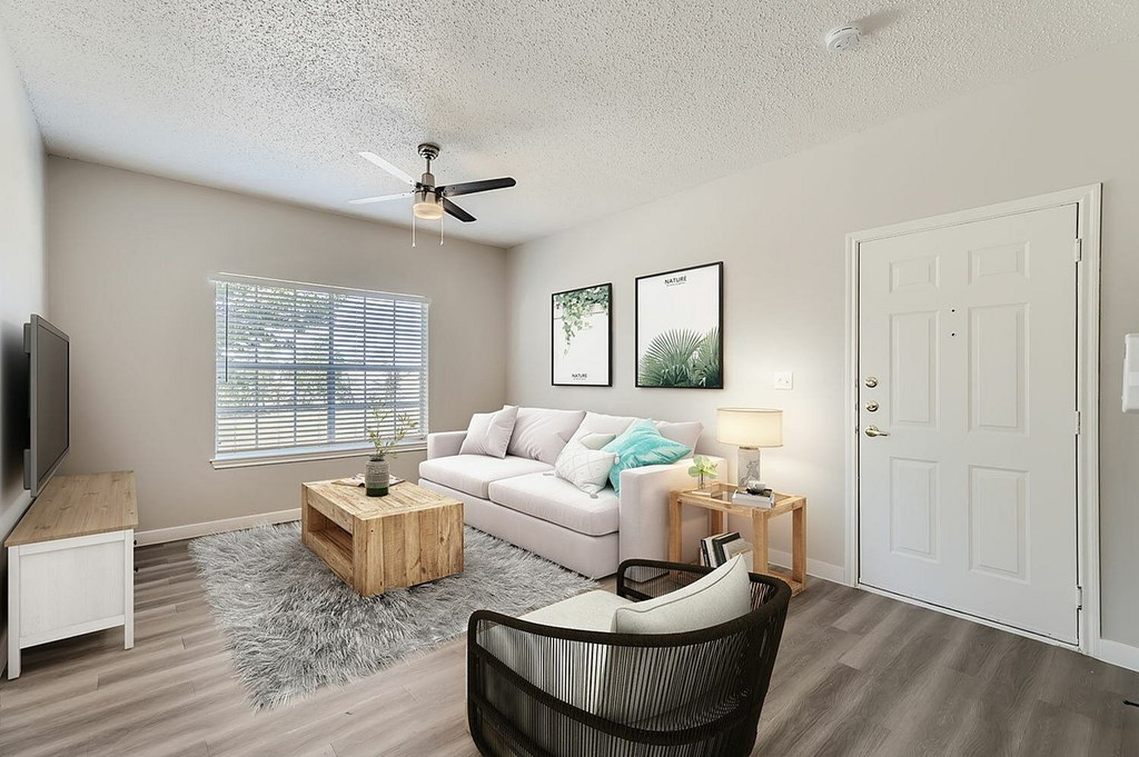 A living room with a white couch, a wooden coffee table, and a ceiling fan.
