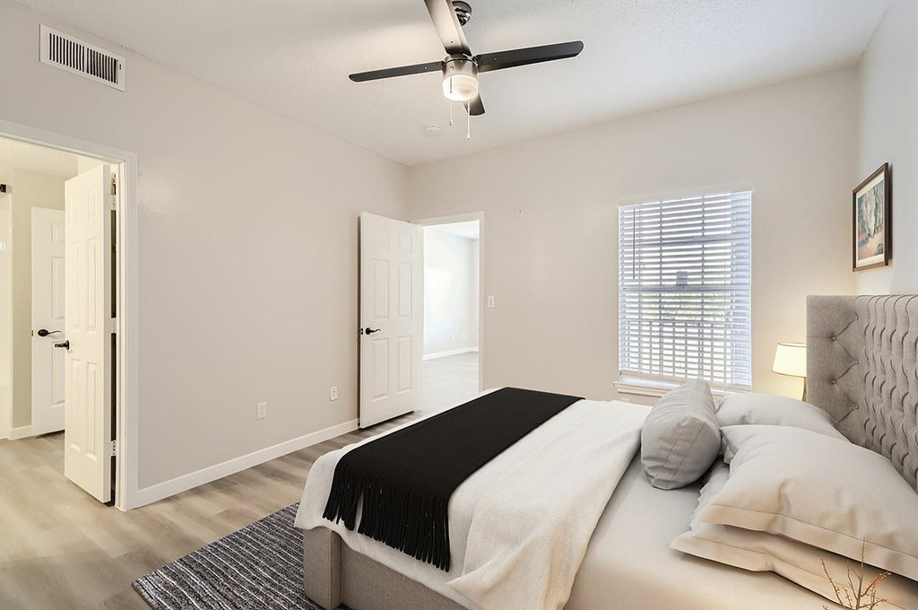 A bedroom with a bed, pillows, and a ceiling fan.