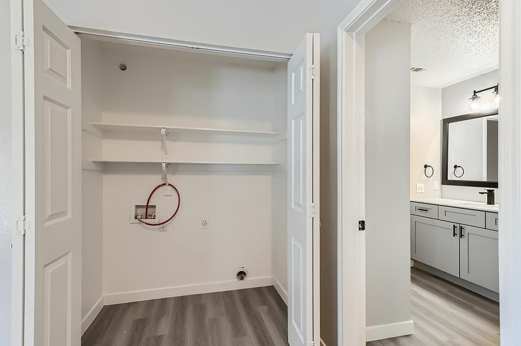 A white door is open to a bathroom and kitchen area.