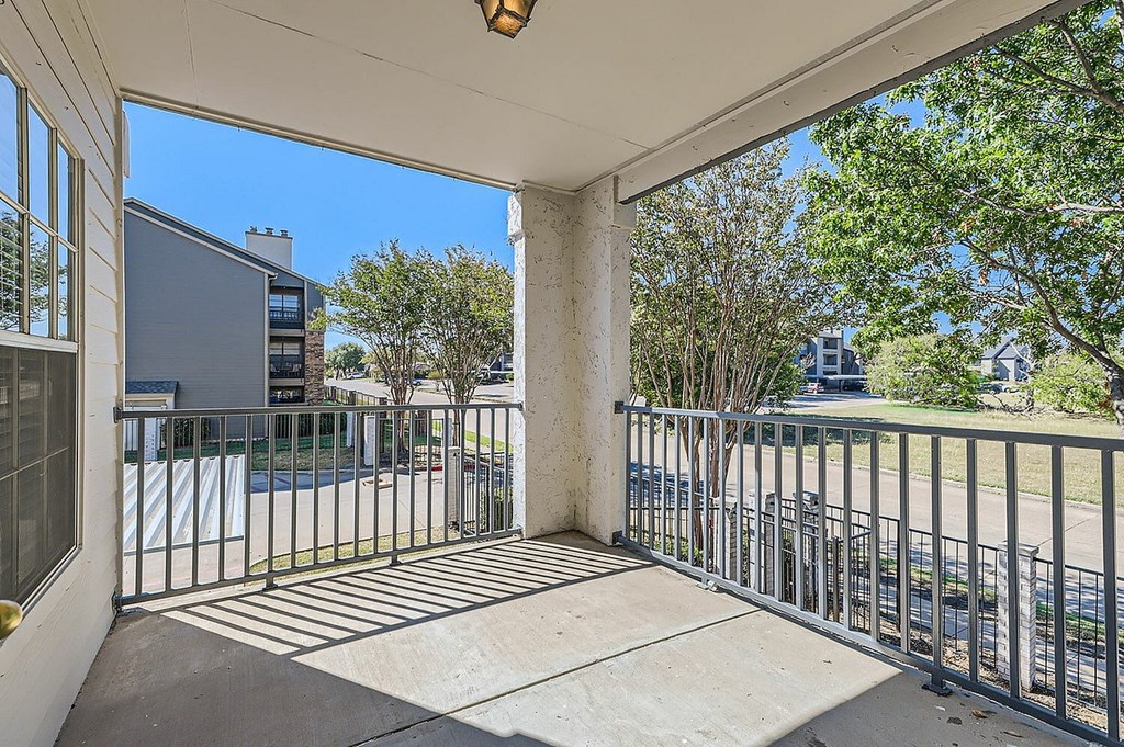 A balcony with a metal railing and a concrete floor.