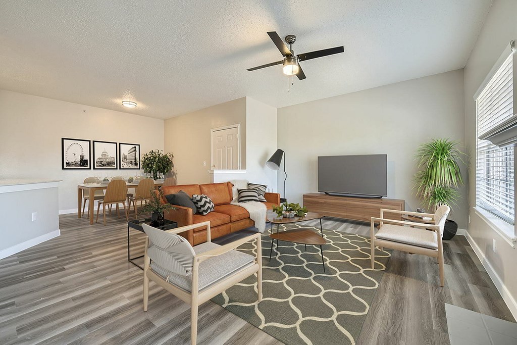 A living room with a television, couch, and chairs.