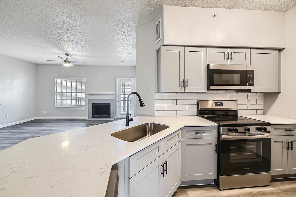 A kitchen with a white counter top and stainless steel appliances.